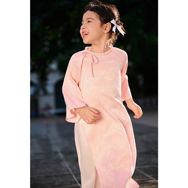 Trong số các lựa chọn hiện có, Áo dài mẹ và bé cách tân dáng suông lụa gấm thiết kế dây cổ tết đính nơ tay lỡ loe đang nhận được phản hồi tích cực vì sự cân bằng giữa truyền thống và tiện lợi. (Ảnh 5)